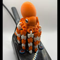 A 3D-printed orange octopus-shaped knob on a black console with blue buttons, photographed on a white background.