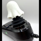 A novelty ghost-shaped joystick with a white ghost head and black stalk, mounted on a glossy black base with buttons and a power cord, shown against a light gray background.