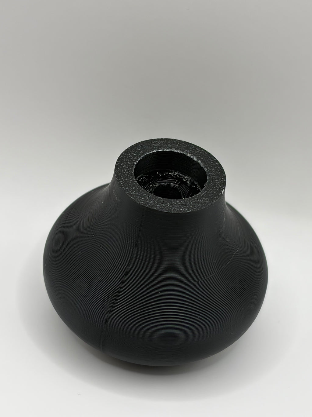 Black textured ceramic vase top with open mouth and ridged surface detail