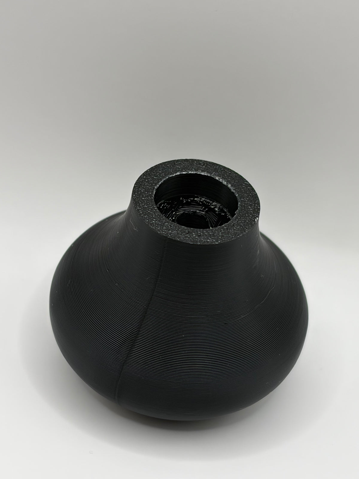 Black textured ceramic vase top with open mouth and ridged surface detail