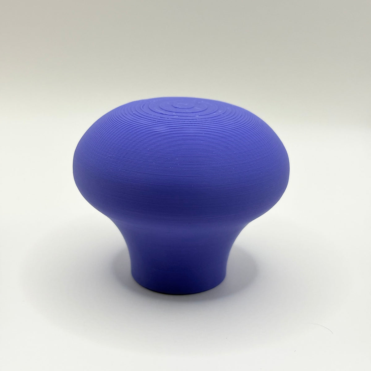 A single mushroom-shaped blue product, likely a 3D-printed knob or handle, centered on a light gray studio background.