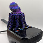 A joystick stick with a purple and blue octopus decoration on the top, featuring multiple button controls on a black base against a plain white background.